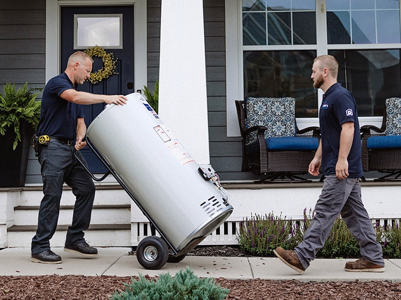 Two men installing a water heater outside a house.
